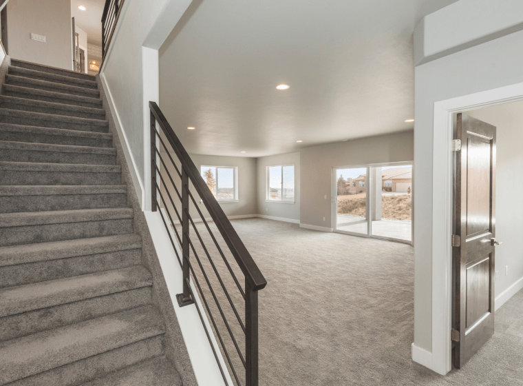light grey basement with grey stairs and dark brown doors and glass doors