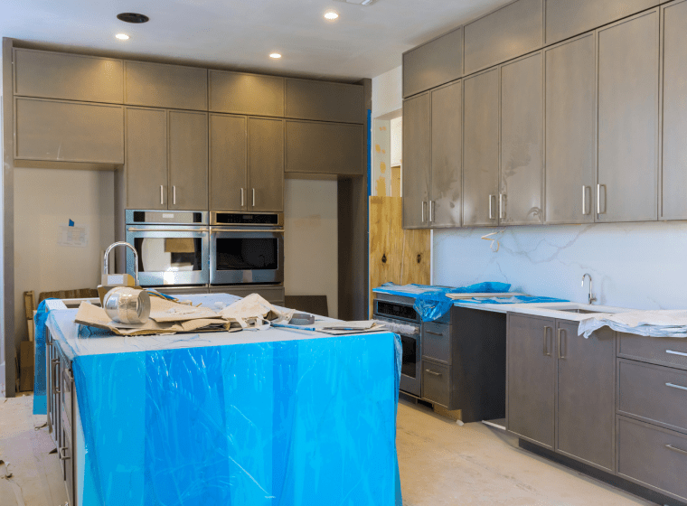white kitchen being remodeled with grey cabinets and circle ceiling lights